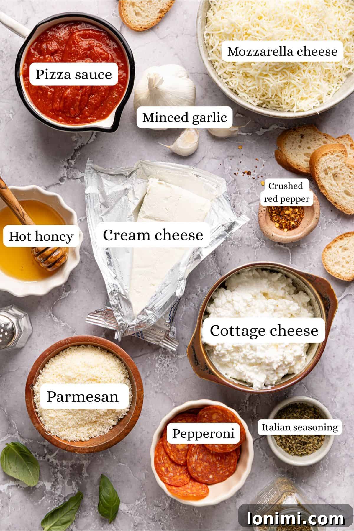 High protein pizza dip ingredients meticulously labeled and arranged in nesting bowls on a sleek light gray countertop, ready for preparation.