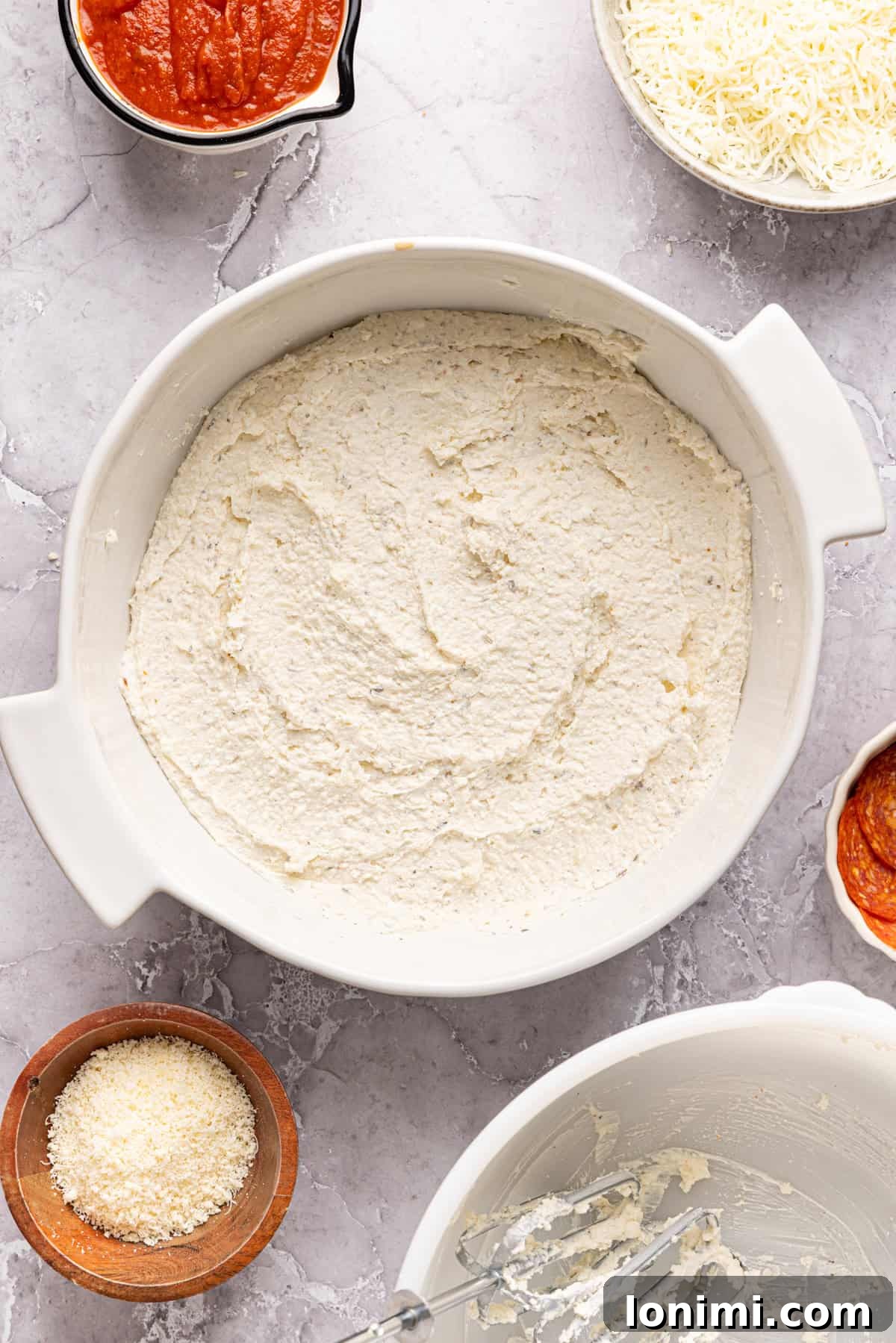 The smooth, blended high protein pizza dip mixture evenly spread out across the bottom of a white pie plate, forming a consistent base layer.