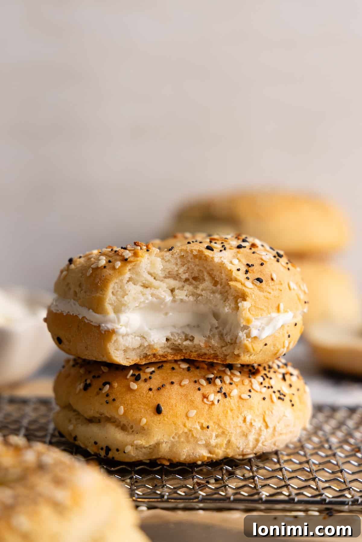 Two cottage cheese bagels stacked on top of each other; the top one is filled with cream cheese.