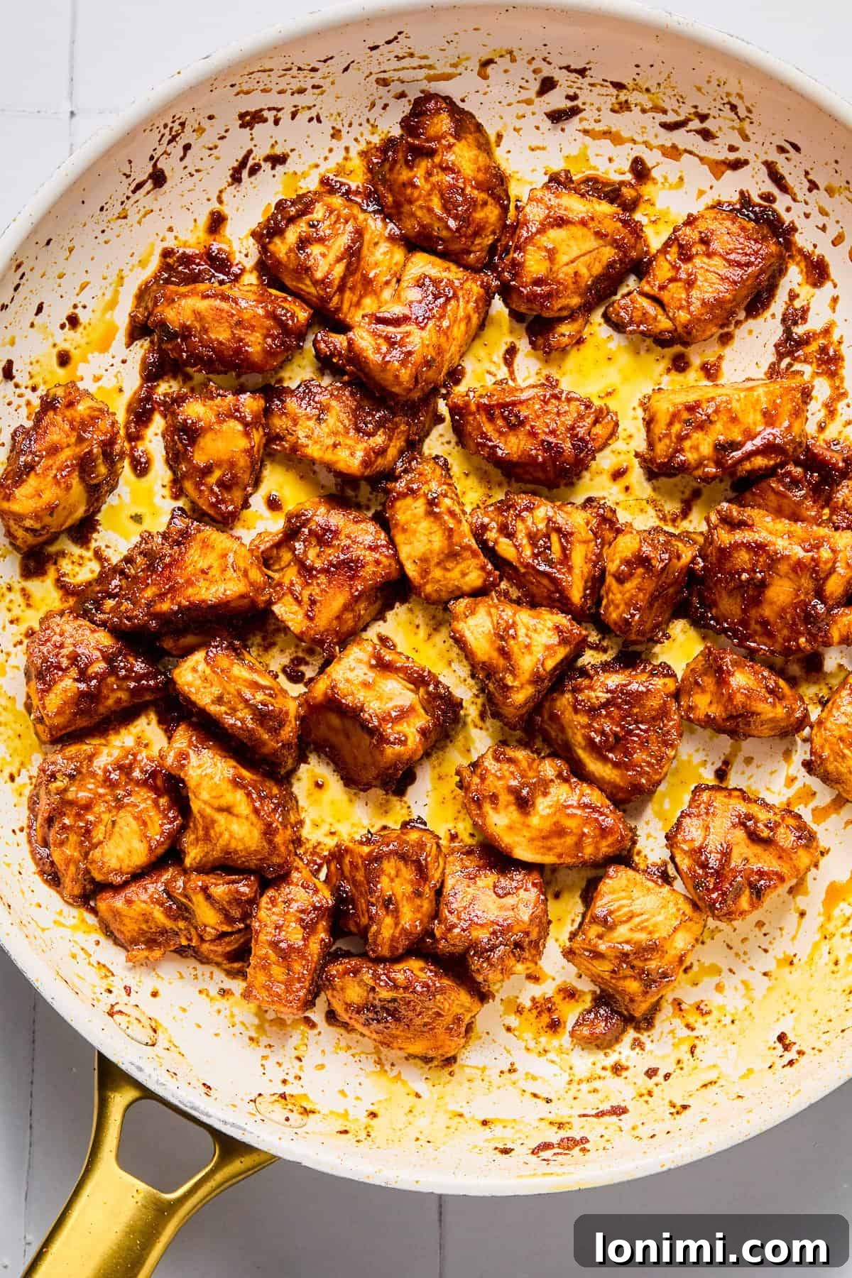 Taco-seasoned chicken breast pieces searing in a hot skillet.
