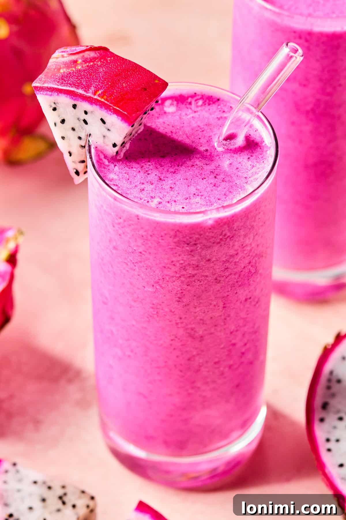 Close-up of a creamy dragonfruit smoothie in a glass with a slice of fresh dragonfruit on the rim.