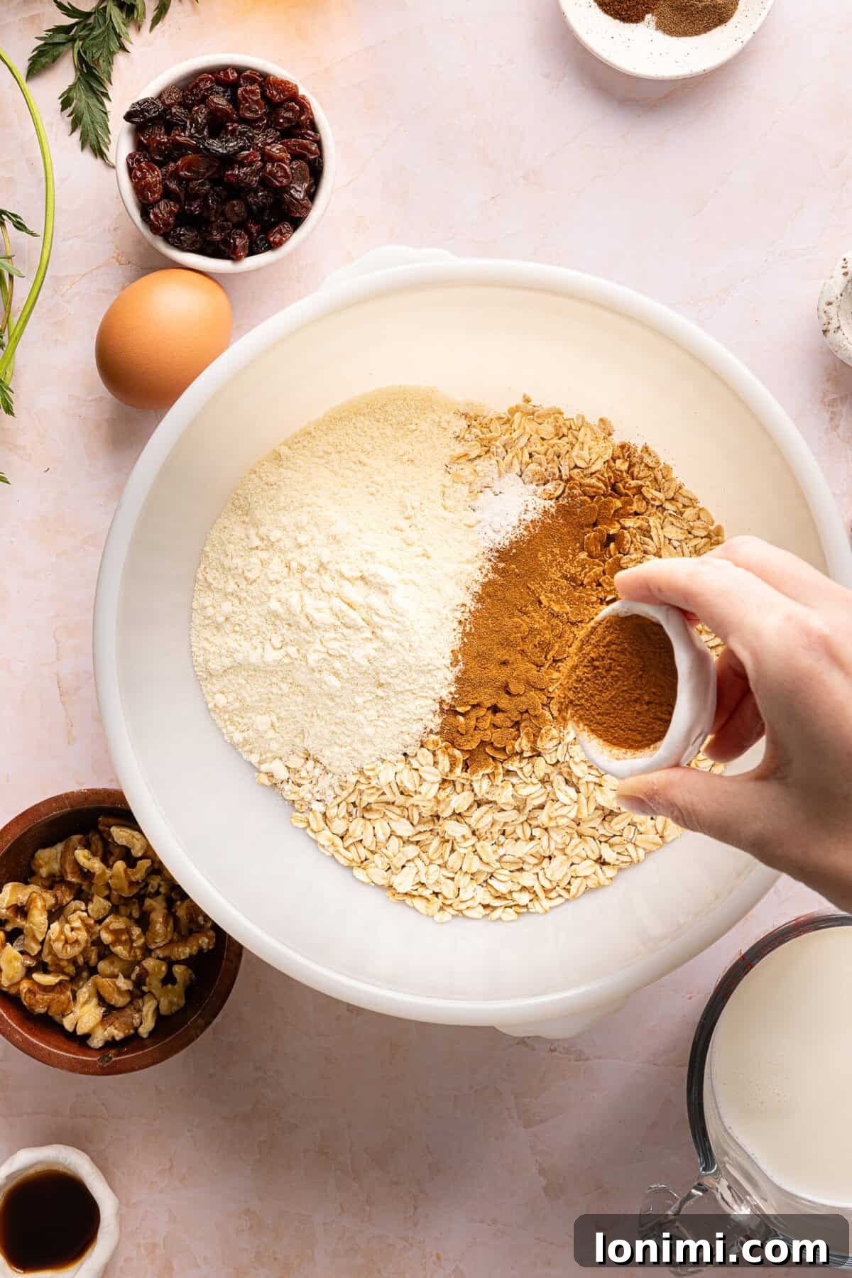 Dry ingredients including gluten-free oats, protein powder, and warm spices ready to be mixed together in a large bowl.