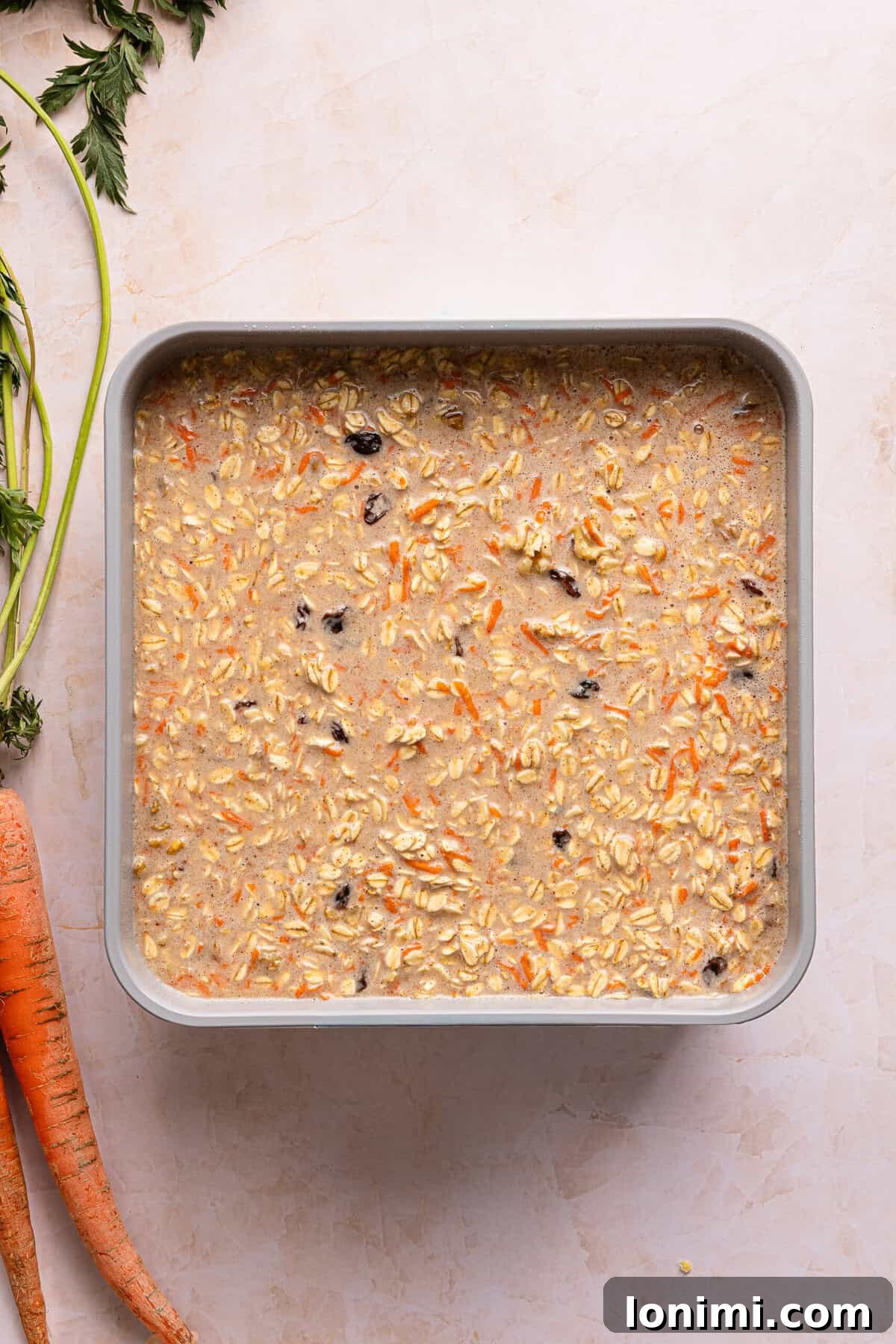 Carrot cake baked oats batter poured into a greased 9x9 metal baking dish before baking.