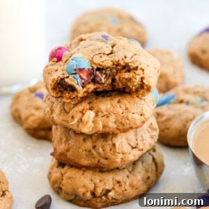 4 monster cookies stacked on top of each other surrounded by m&ms and other cookies