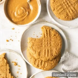 gluten free peanut butter cookies on small white plates with a bowl of creamy peanut butter and a white napkin