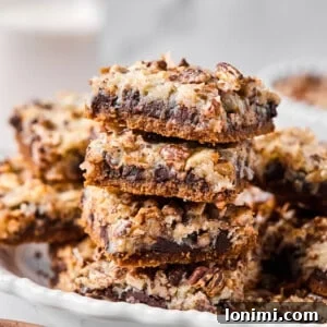 Close-up of a stack of gluten-free magic bar squares showing defined layers of chocolate, coconut, and pecans