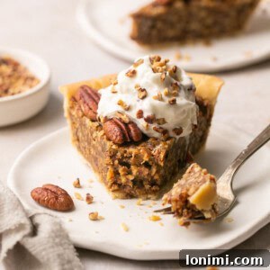 gluten free pecan pie on a plate topped with whipped cream with a fork taking a bite out of it with a piece of pie in the background