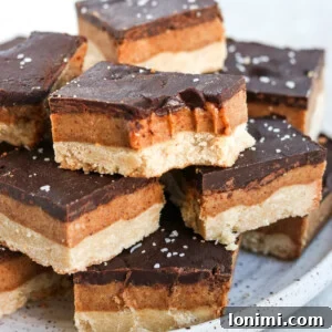 Vegan gluten free millionaire shortbread bars stacked on a plate. One has a bite out of it