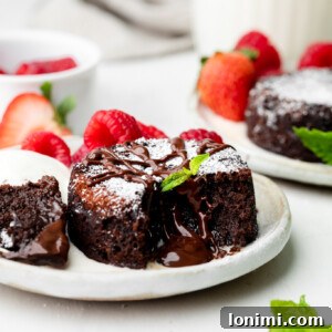 mini chocolate lava cake on a plate with mint leaves and raspberries and strawberries in the background