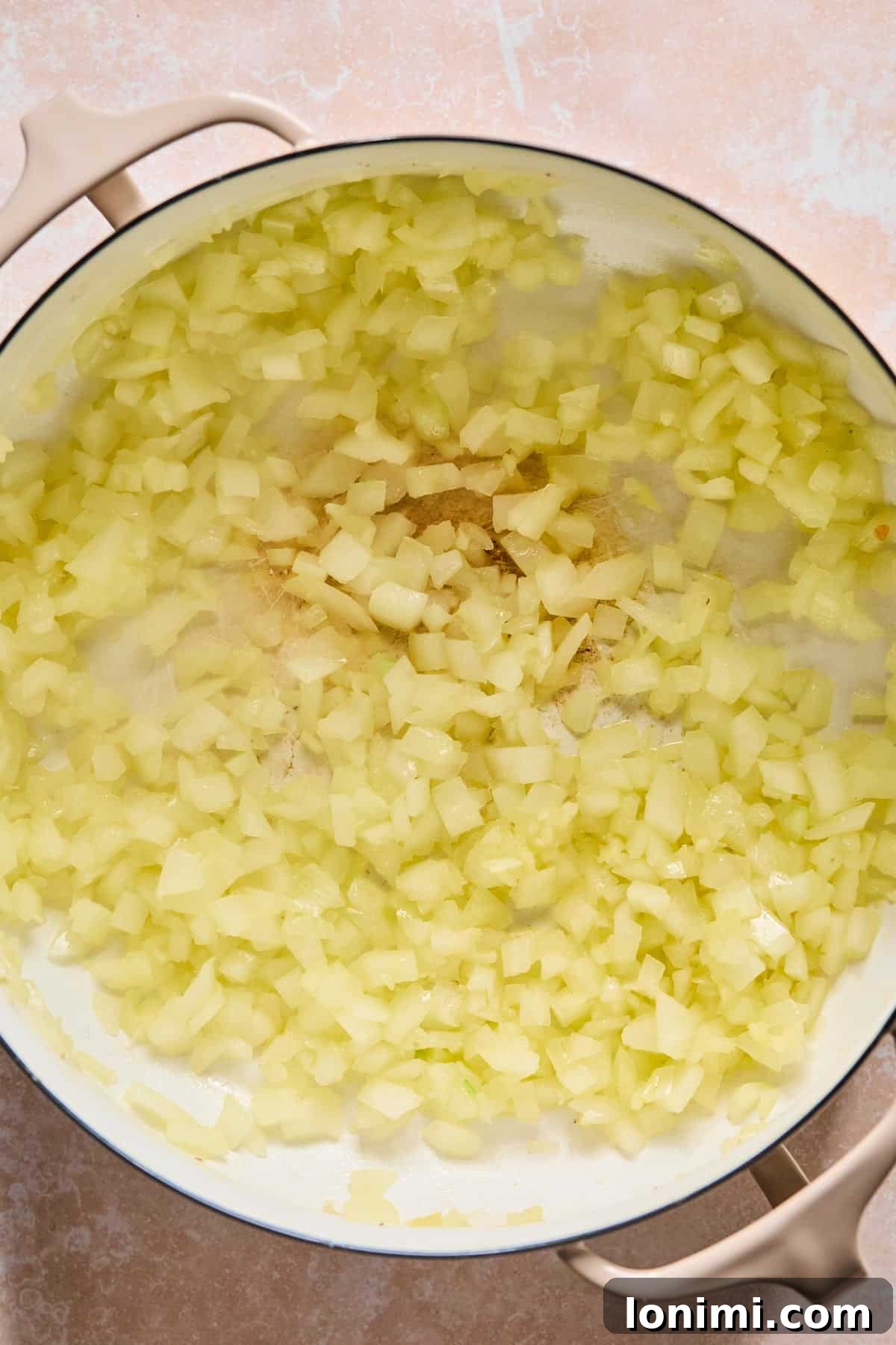 Sautéing diced onion and minced garlic in a Dutch Oven to build aromatic flavors.