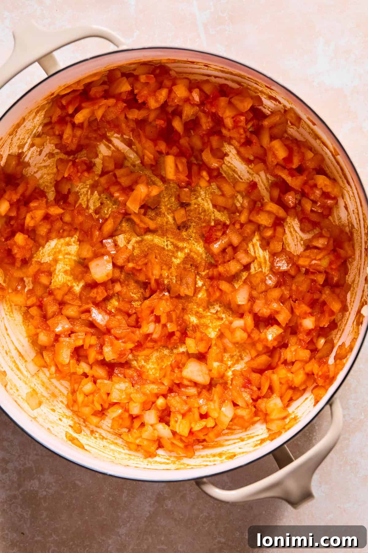Tomato paste added to the Dutch Oven with onion and garlic, stirring to toast and deepen flavor.
