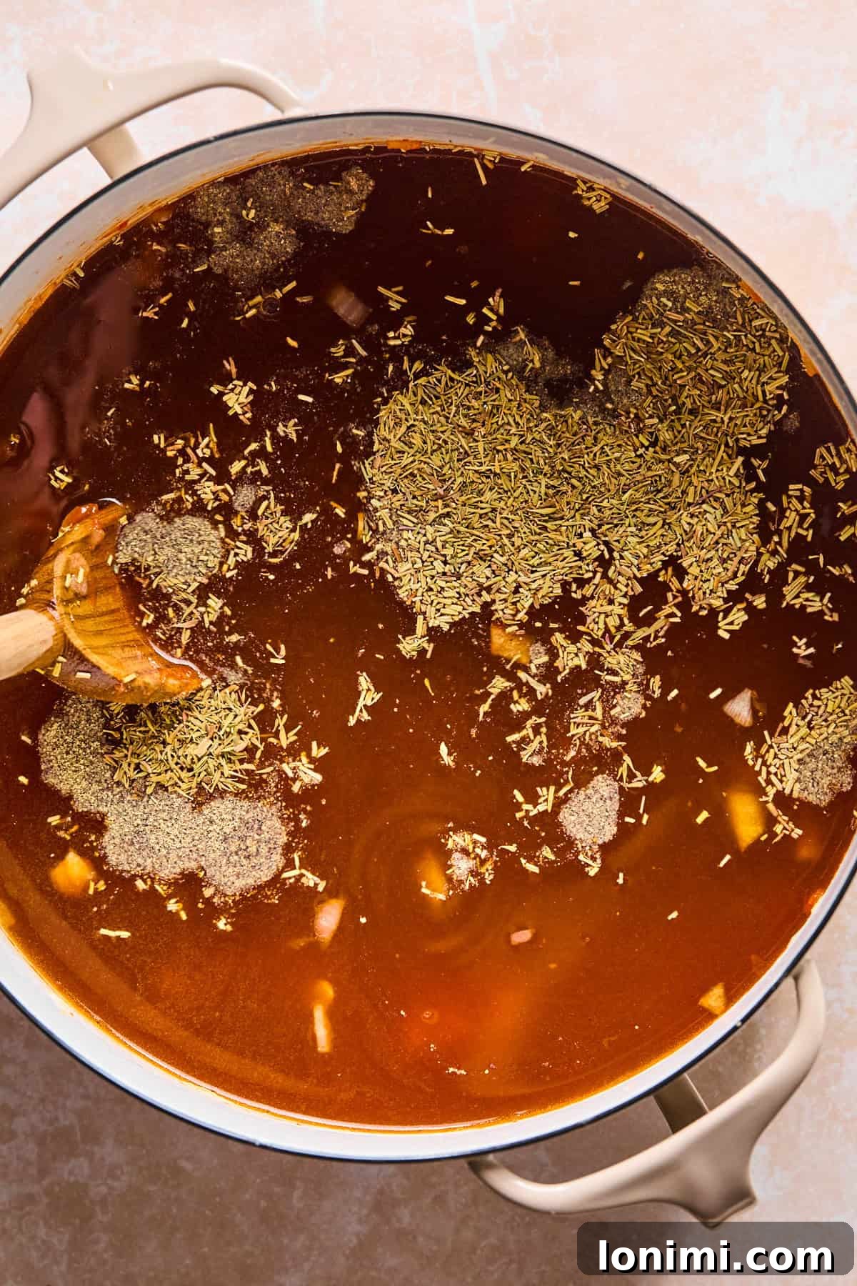 Beef broth, herbs, and cubed potatoes added to the pot, ready to simmer and develop flavor.