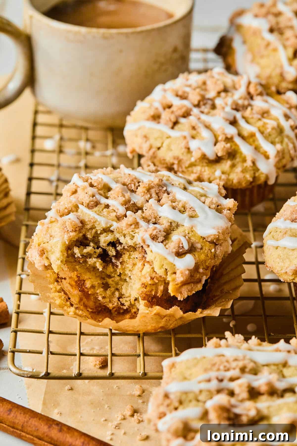 Gluten-Free Coffee Cake Crumble Muffins 8 A close-up of a coffee cake muffin on a cooling rack with a bite taken out, revealing its fluffy interior and cinnamon swirl.