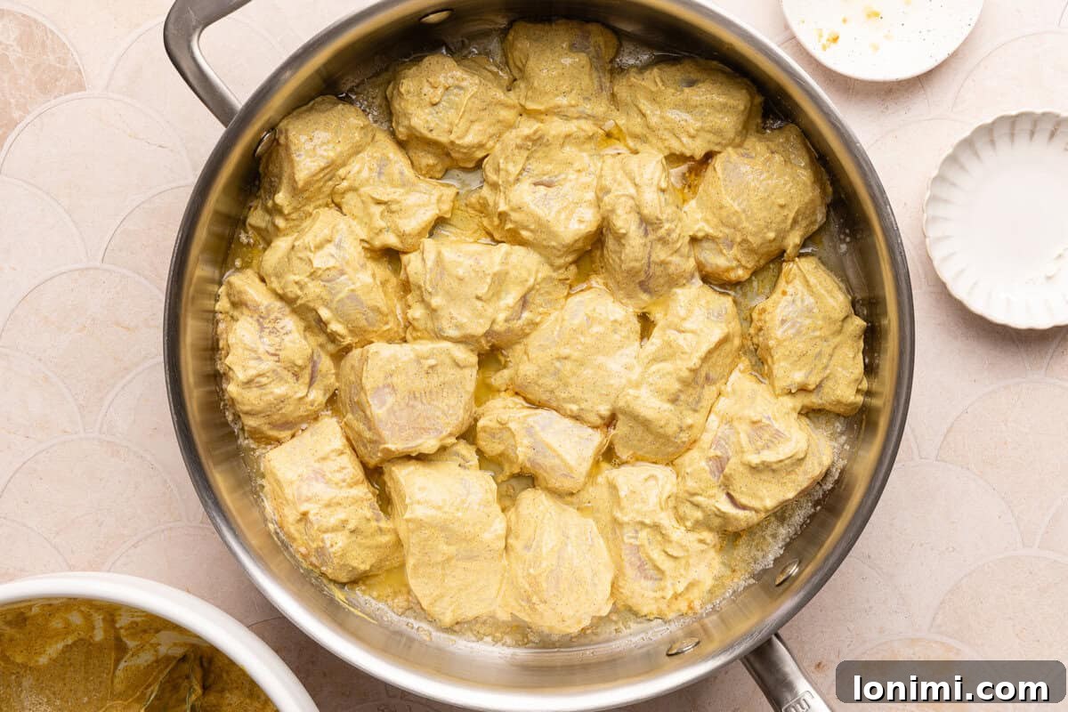 Cubed chicken searing in a large skillet with butter and garlic, developing a golden-brown crust.