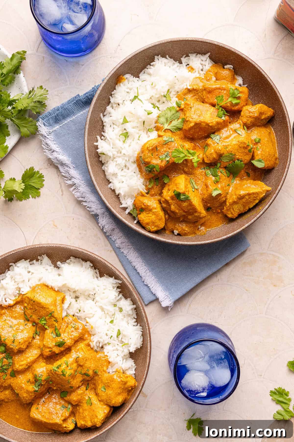 Two bowls of gluten-free butter chicken served over basmati rice, garnished with fresh cilantro, ready to be enjoyed.