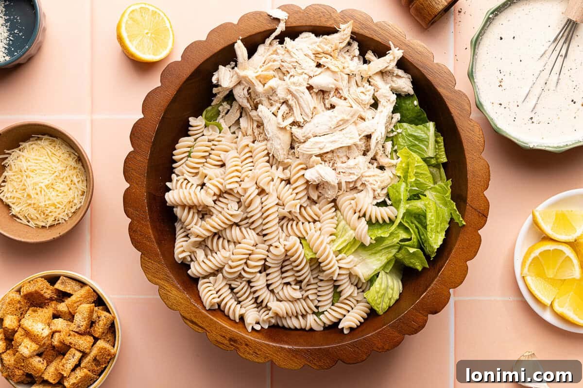 pasta, chicken, and lettuce in a wooden bowl