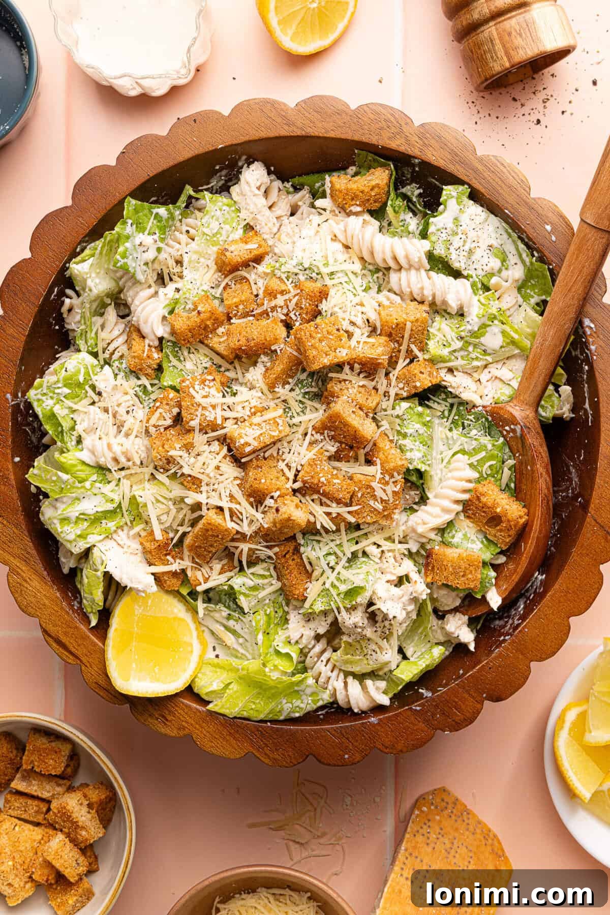 chicken caesar pasta salad topped with croutons in a wooden bowl