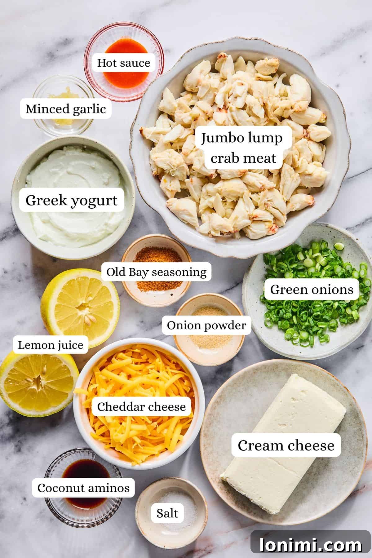 Ultimate Creamy Crab Dip Warm or Cold 3 Crab dip recipe ingredients labeled and laid out in nesting bowls on a light gray and white countertop.