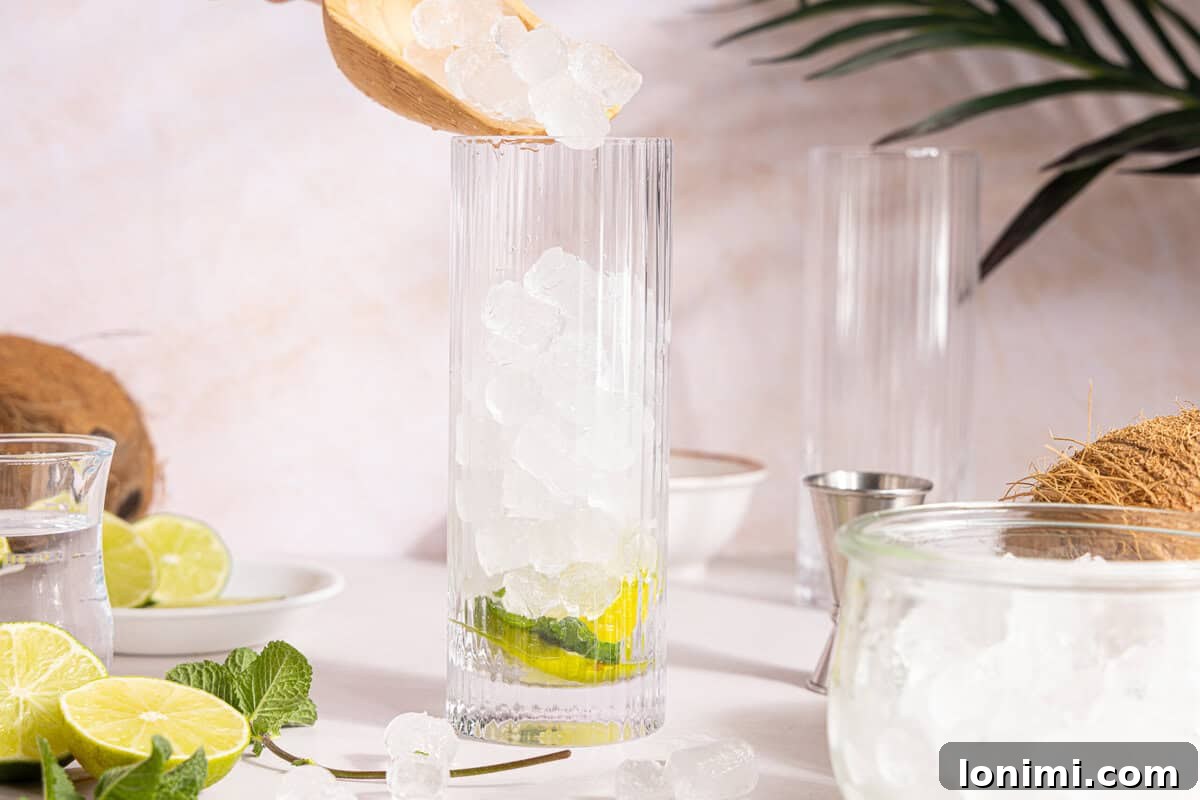 Ice cubes being poured into a cocktail glass, filling it three-quarters full