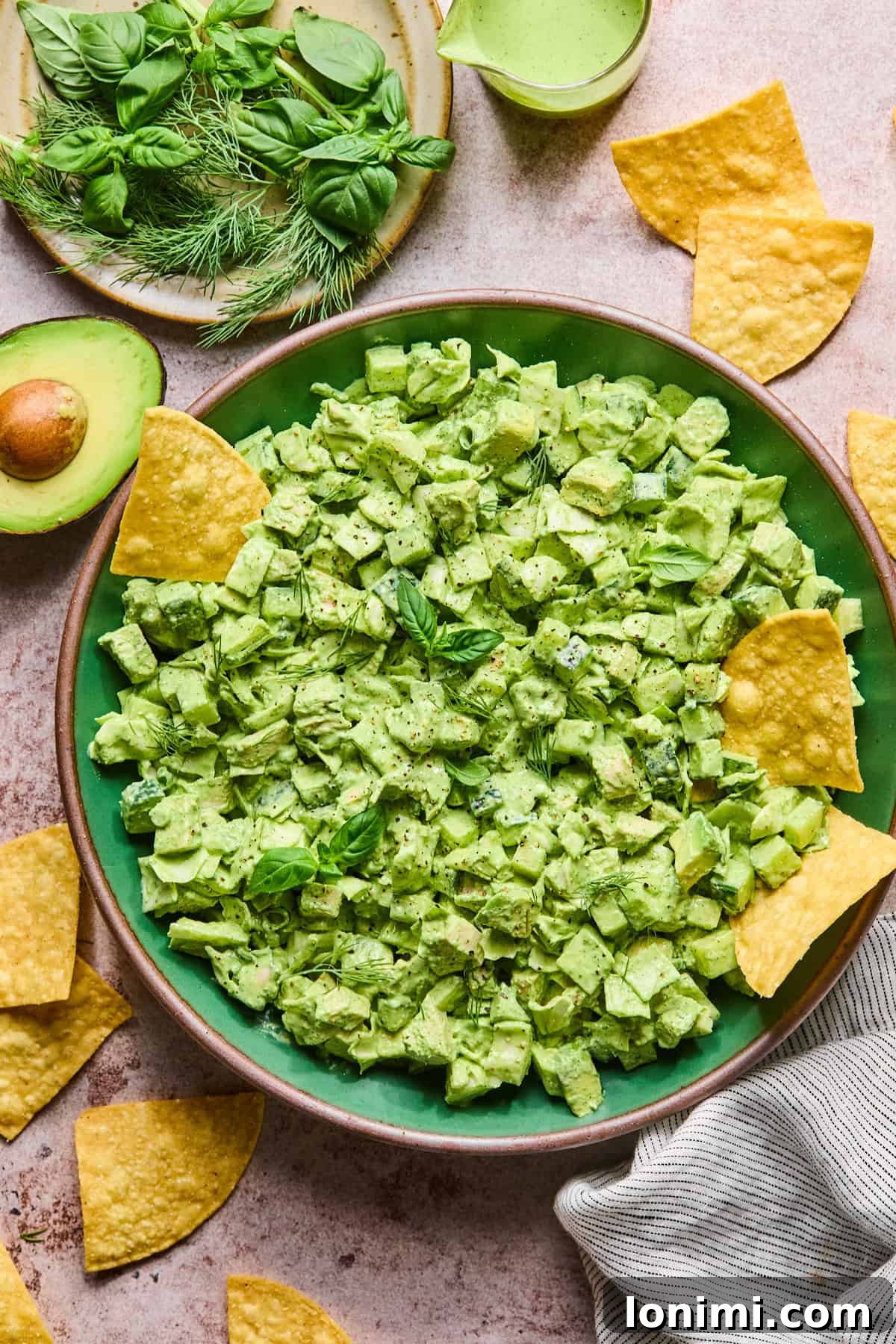 A large bowl of Green Goddess Chicken Salad served with gluten-free tortilla chips and fresh avocado slices.