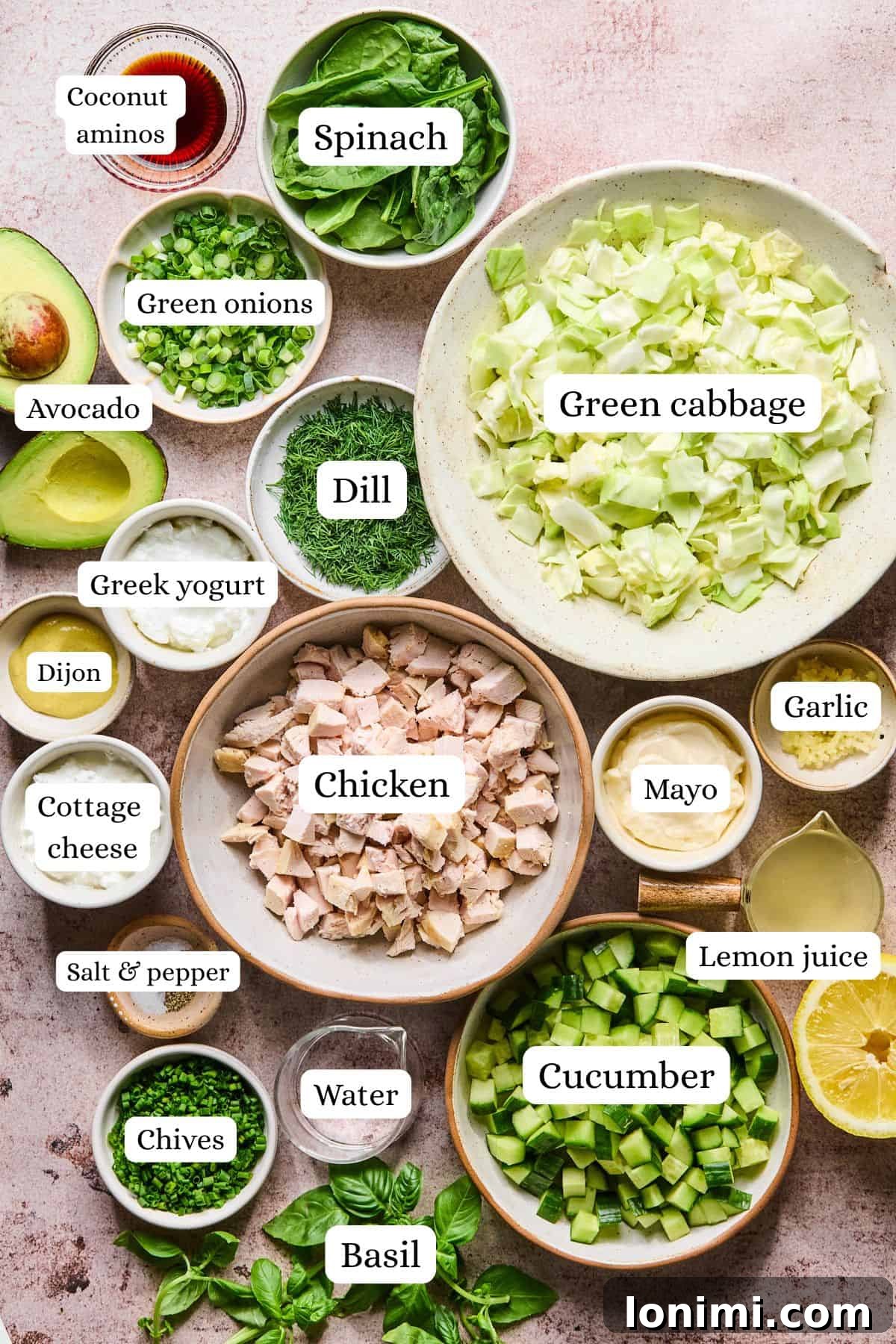 All the fresh ingredients for the chicken salad and dressing arranged neatly in bowls on a white countertop.