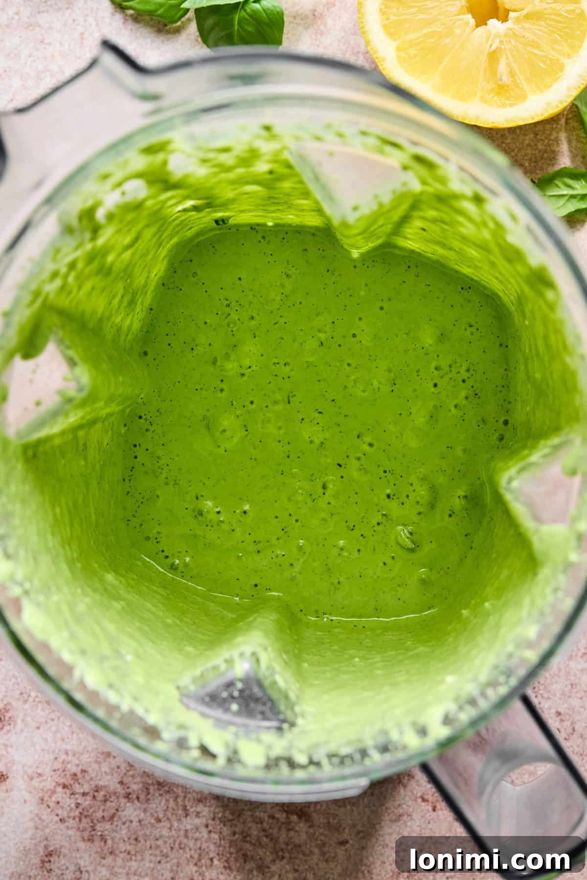 The vibrant green goddess dressing being blended until smooth and creamy in a high-speed blender.