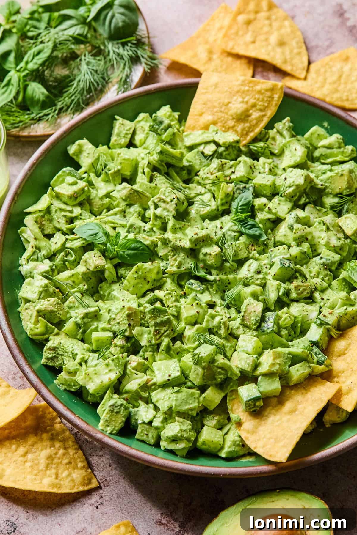 A side-view of the vibrant green chicken salad in a white bowl, showing its creamy texture.