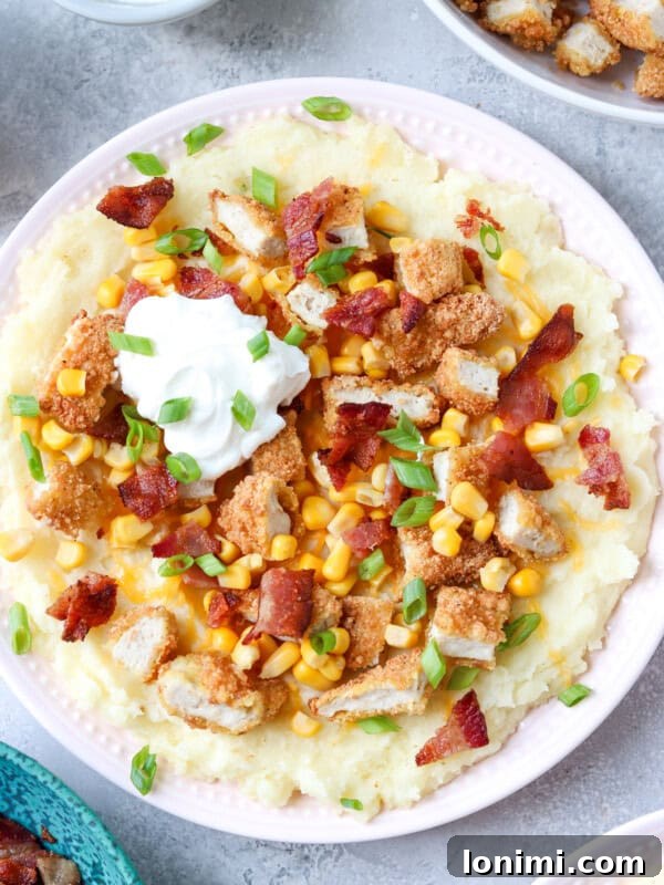 gluten free loaded potato bowl with mashed potatoes, cheese, bacon, corn, chicken tenders, bacon, and green onions with a dollop of sour cream