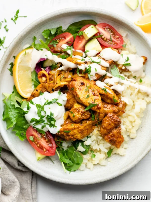Sheet Pan Chicken Shawarma Bowl with cauliflower rice, tomatoes, parsley, lemon, tzatziki, and lemon tahini dressing