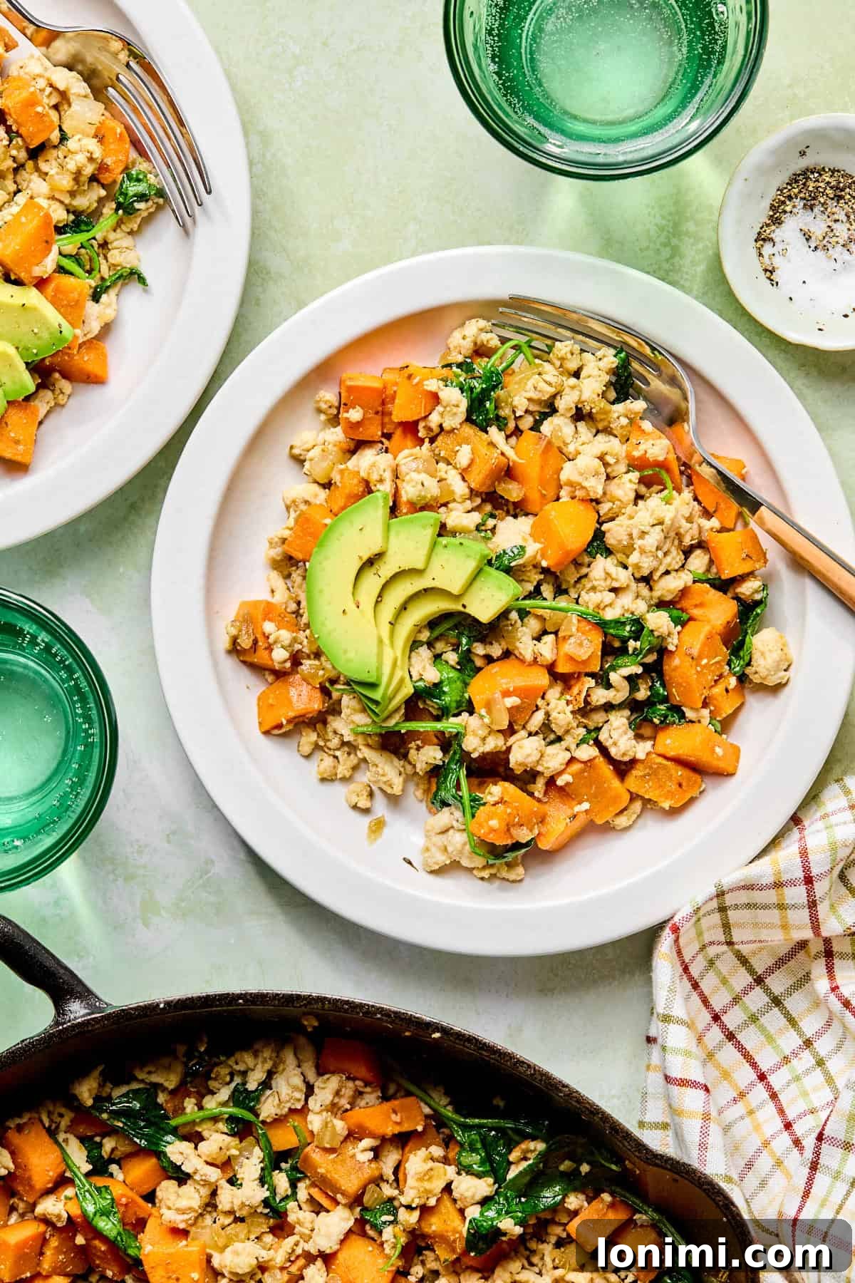 sweet potato breakfast hash in a white bowl next to a skillet