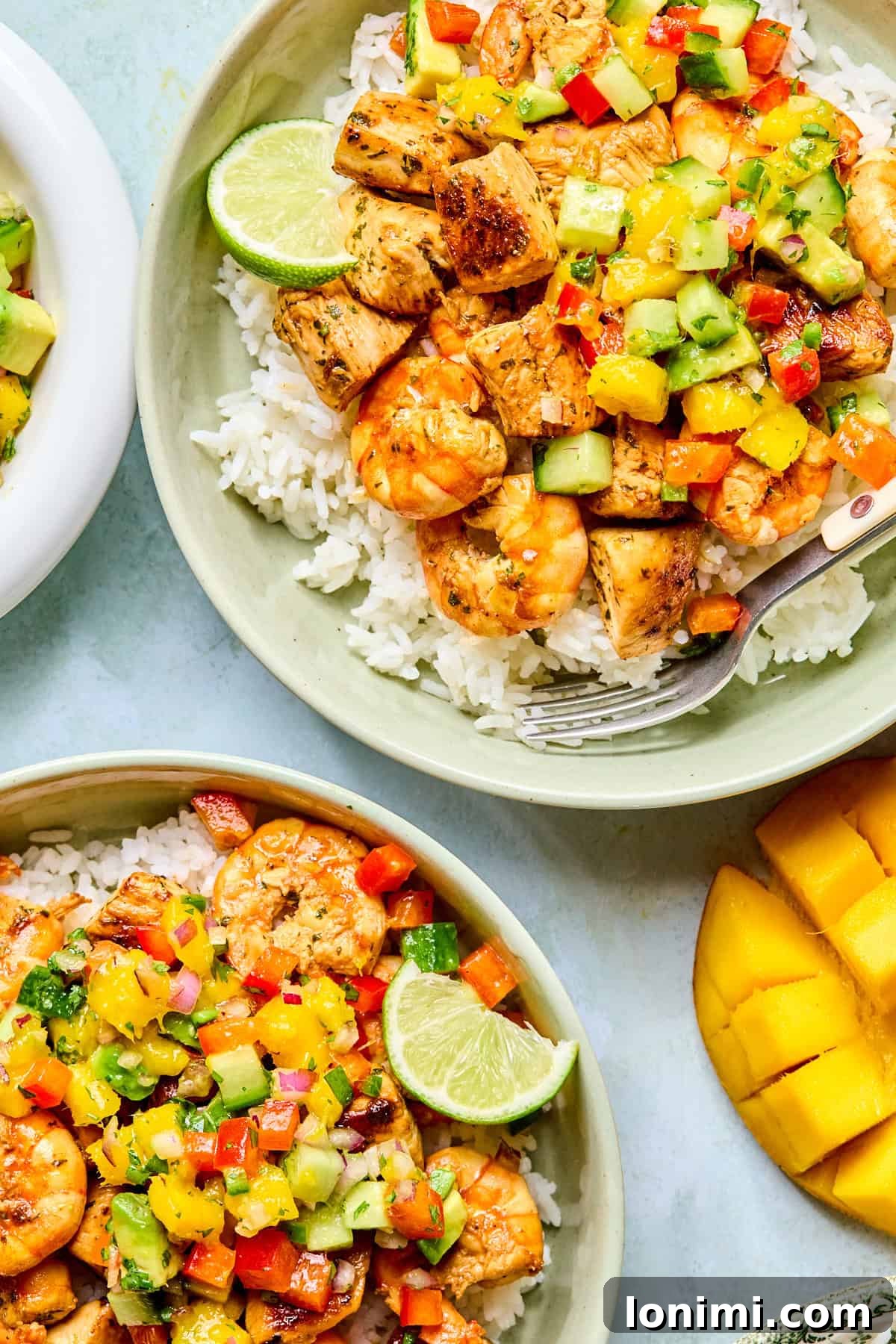 2 bowls of chicken and shrimp over rice with mango salsa