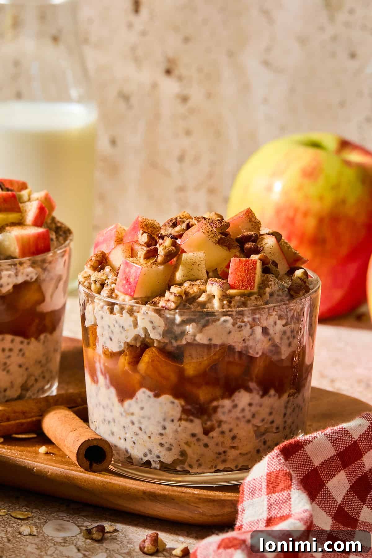Apple Pie Protein Overnight Oats 2 apple pie overnight oats in a glass jar topped with apples and walnuts